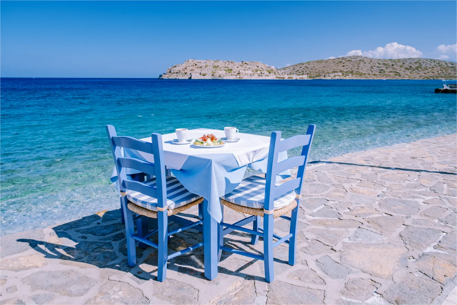 Ένα τραπέζι με μπλε καρέκλες, δίπλα στη θάλασσα στο Λασίθι της Κρήτης